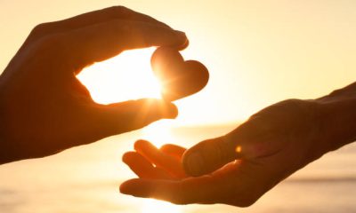 Hand passing heart to another.